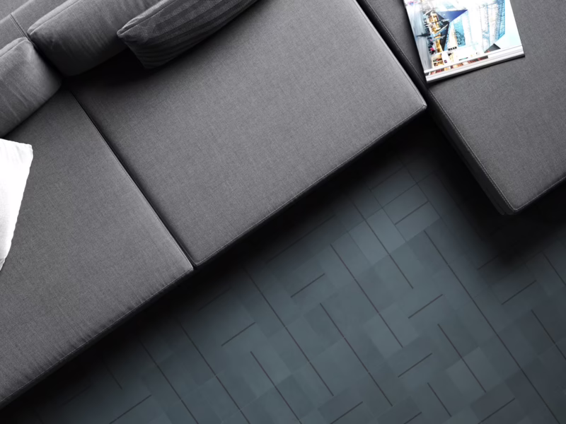 Suelo de salón contemporáneo con pavimento de azulejos artesanales Verde Petróleo y línea antracita en contraste con mobiliario gris