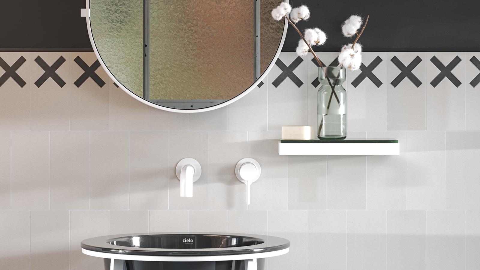 Pared del cuarto de baño realizada con azulejos de base blanca y una decoración en color negro