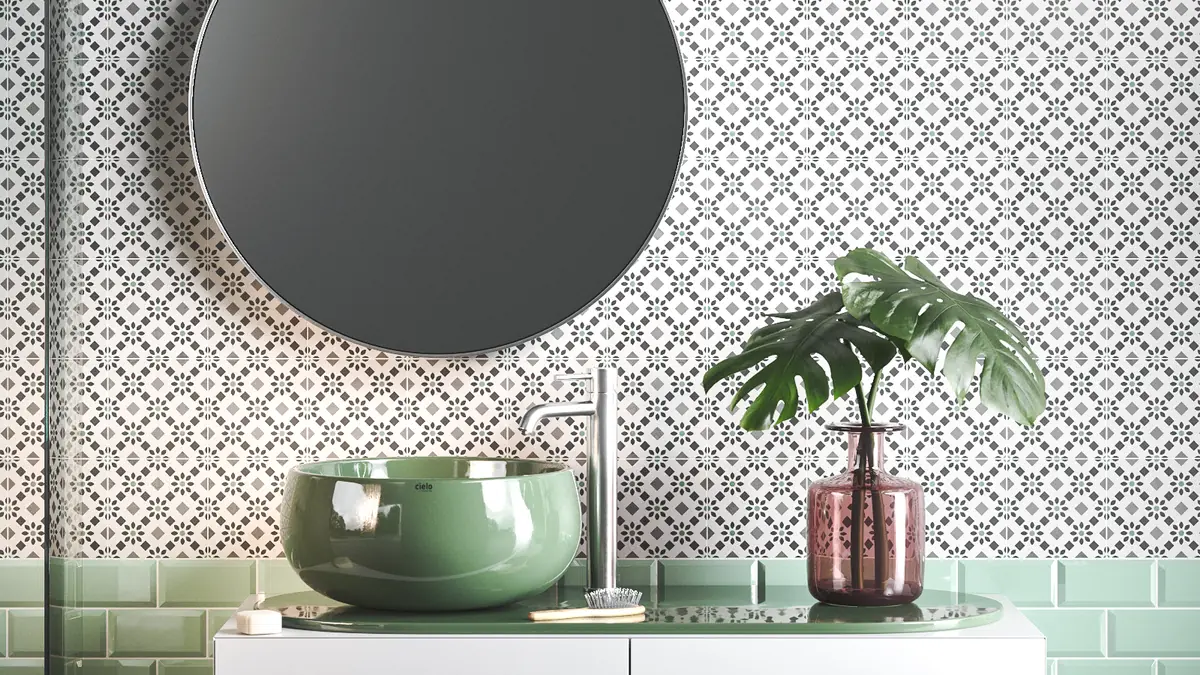 Pared del baño con azulejos decorados de fondo blanco y diseño en tonos grises y verdes
